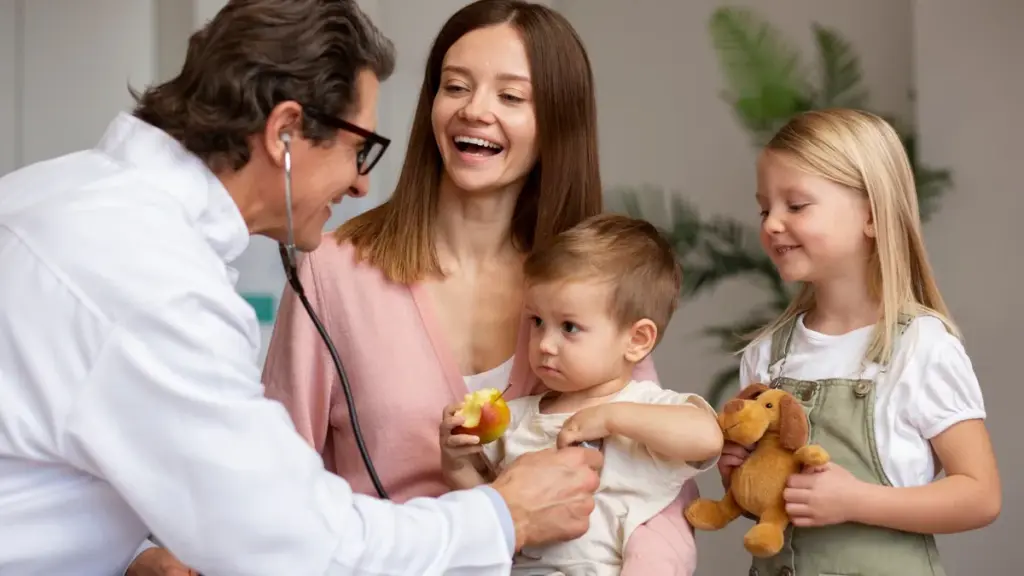 Saúde na família: como reconhecer necessidades diferentes e encontrar o atendimento adequado Médico examina uma criança no colo da mãe enquanto a irmã observa no consultório
